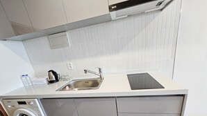Una cuina compacta amb rentadora integrada, un rentaplat i una superfície de treball.