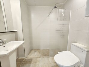 Une salle de bain moderne équipée d’une douche, de toilettes et d’un lavabo.