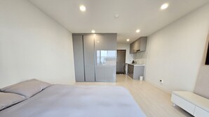 Un dormitori modern amb un llit gran, un vestidor i una cuineta.