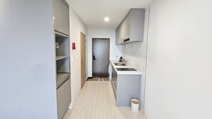 Passadís estret amb una cuineta a la dreta, una porta al final i un gresol a prop del rentapeus.