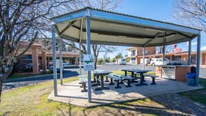 A covered picnic area with benches and a smoking permit sign. - Orange Motor Lodge (Orange)