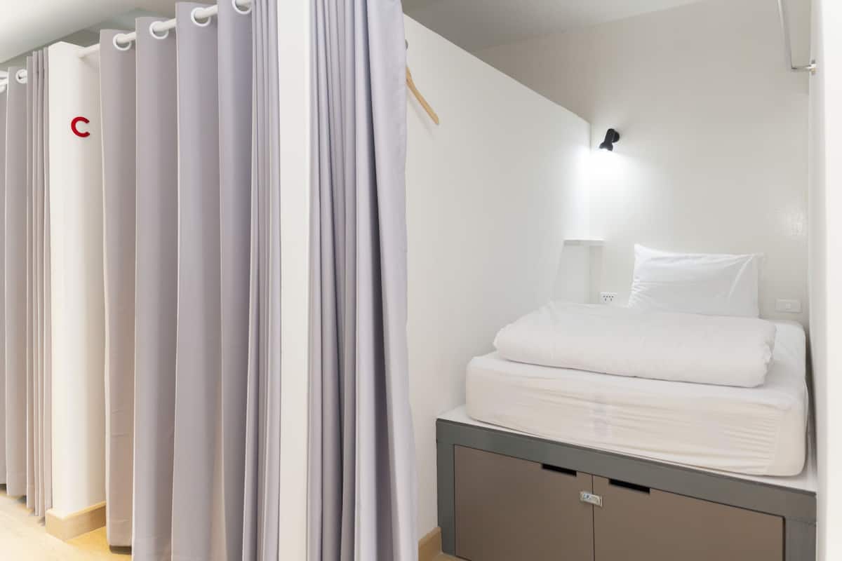 A hotel room with a bed, a bedside table, and a wardrobe.