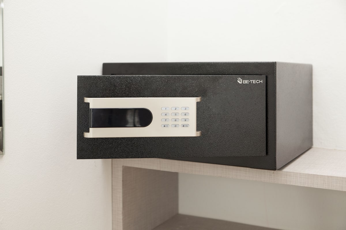 A black safe with a keypad and the brand name "BE-TECH" on it, placed on a shelf.