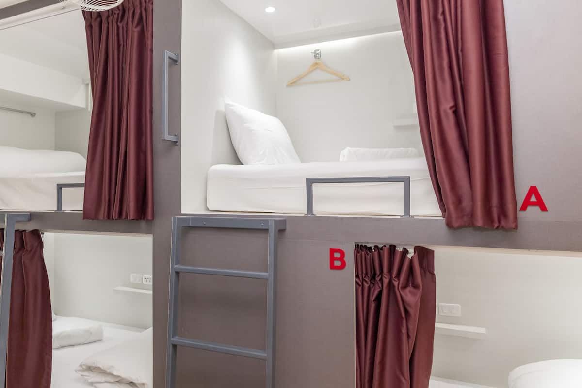 A bunk bed room with a ladder, a white mattress, and a hanging wooden hanger.