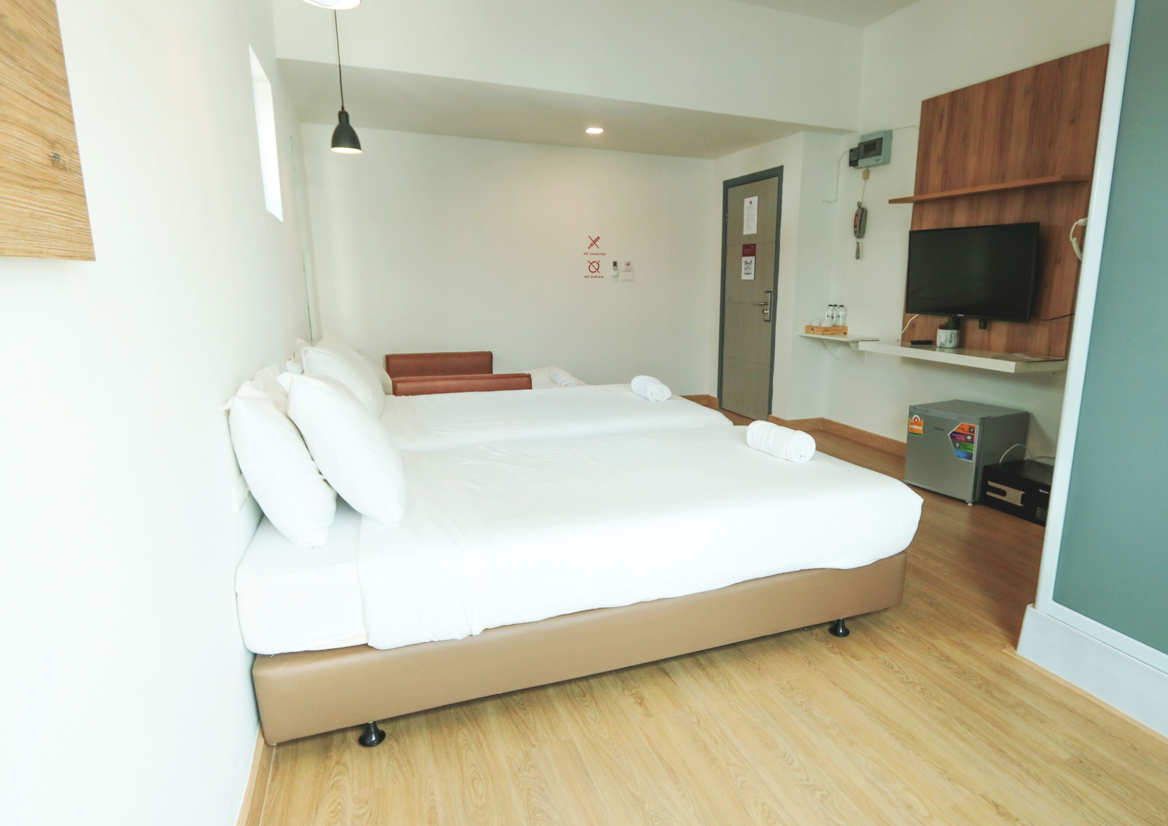 A modern hotel room with a large bed, a wooden floor, a TV, and a small desk.