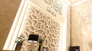 A lobby with a decorative wall, a reception desk, and a chandelier.