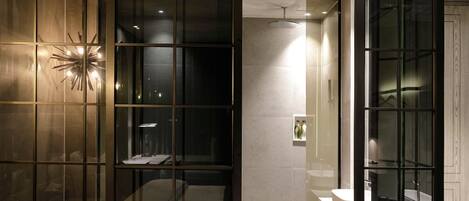 Un baño moderno con separador de vidrio, lámpara con forma de estrella y zona de ducha a la vista.