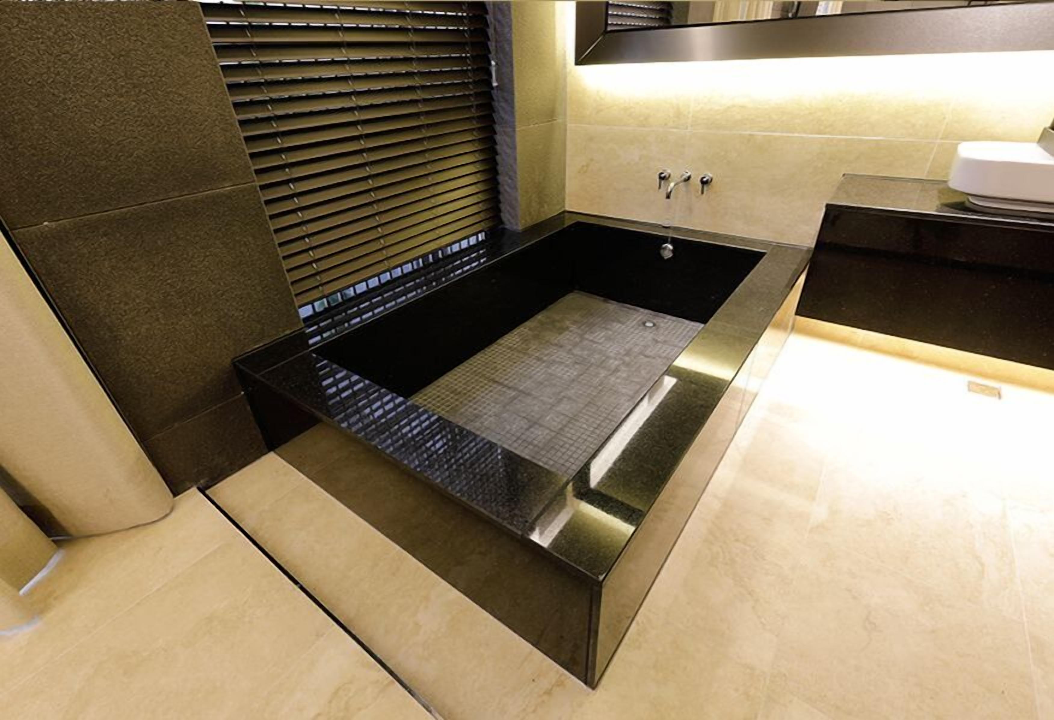A modern bathroom with a large black bathtub, a shower area, and a toilet.