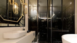 A modern bathroom with a white sink, a large mirror, and a glass-enclosed shower area.