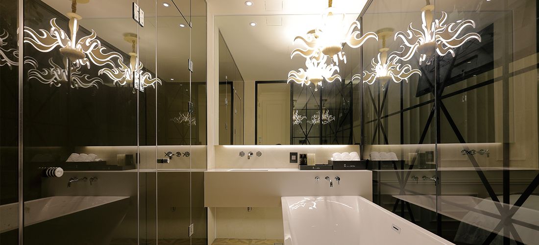 Un baño moderno con separadores de vidrio, lavamanos blancos y luminarias originales.