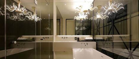 Un baño moderno con separadores de vidrio, lavamanos blancos y luminarias originales.