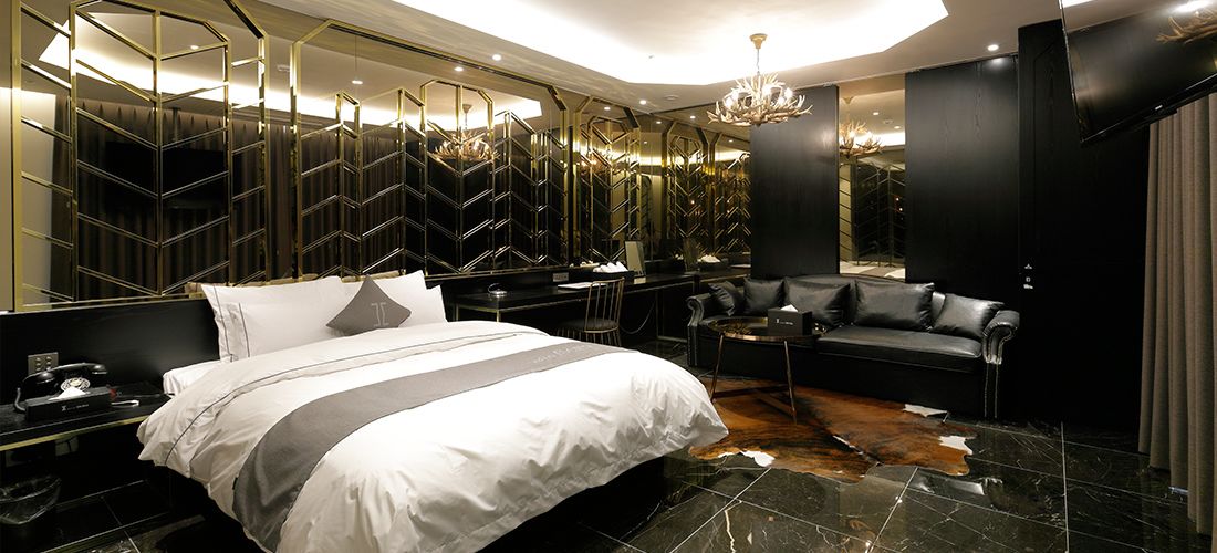 A modern hotel room with a large bed, a seating area, and a mirror wall.