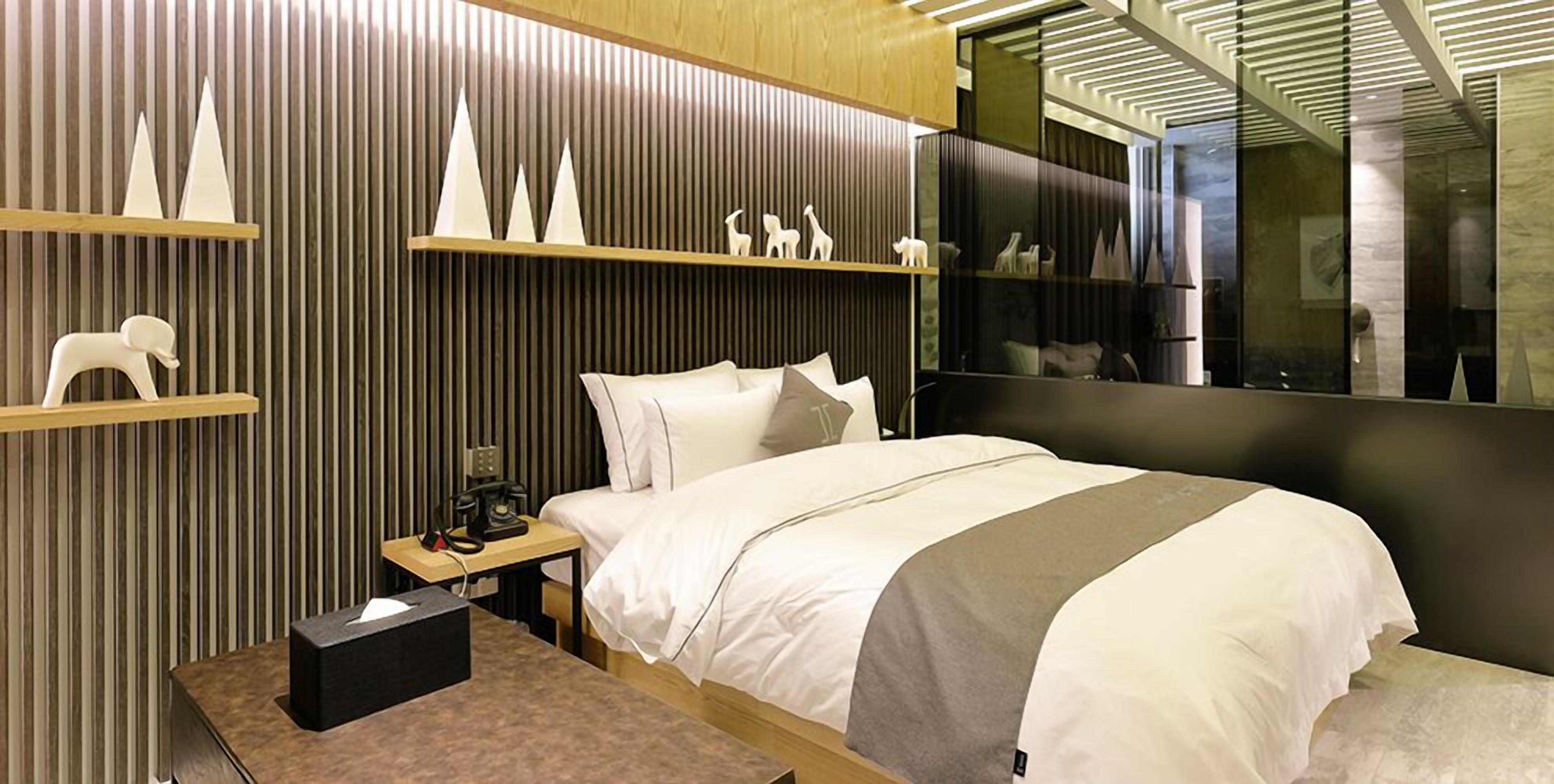 A modern hotel room with a bed, bedside table, and a mirror.