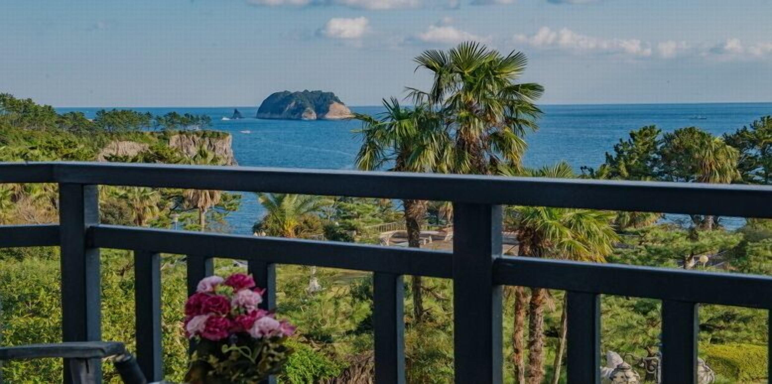 Una vista costiera con una palma e una piccola isola all'orizzonte.