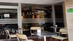 Un restaurante con un letrero que dice "BAR - RESTAURANTE HOSTAL LUCIMAR" y varias mesas y sillas en su interior.