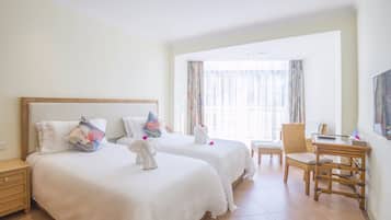 A hotel room with two beds, a desk, a chair, and a large window with curtains.