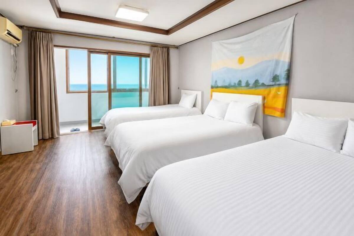 Une chambre d’hôtel avec deux lits, une grande fenêtre et un tableau au mur.