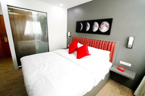 A hotel room with a large bed, red and white striped headboard, and a wall-mounted artwork of the moon phases. - Coco at 20 (Bangkok)