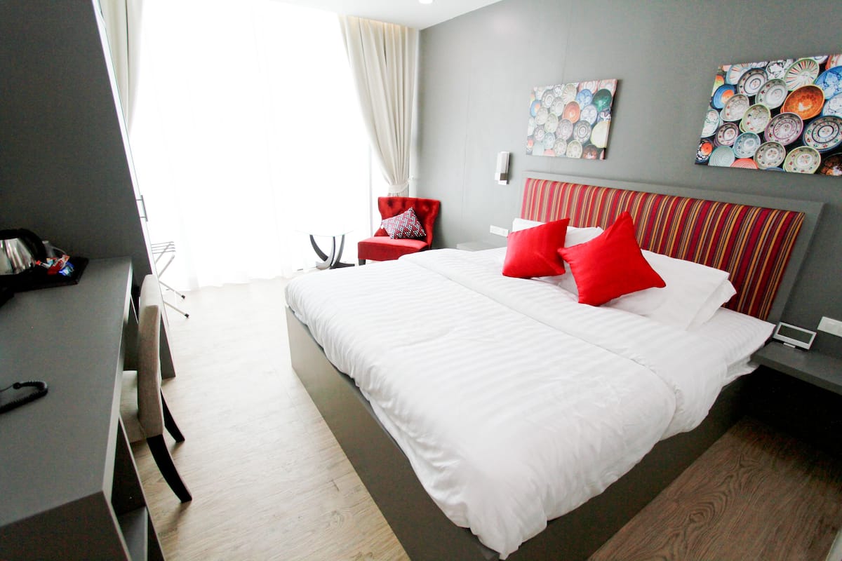 A modern hotel room with a large bed, a red chair, and a wall decorated with plates.