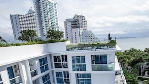 A modern high-rise building with multiple balconies, large windows, and a view of the sea. - Serenity Condo Wongamat by Patsamon (Pattaya)