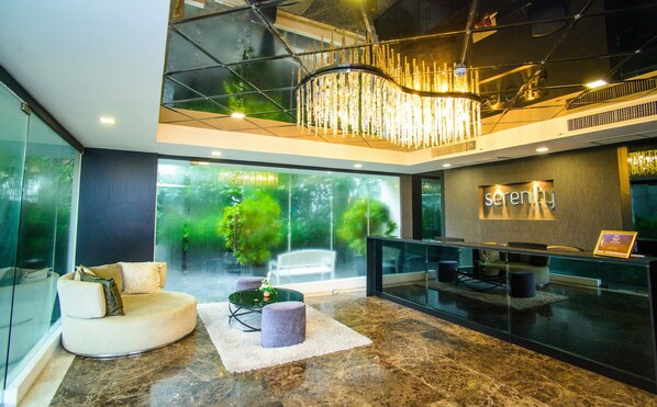 Eine moderne Lobby mit einer Rezeption, einer Sitzecke und einer großen Glasscheibe mit Blick auf Grünflächen.