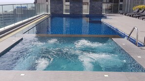 Ein Dachpool mit klarem, blauem Wasser, Steinpfeilern und einer Glasreling.