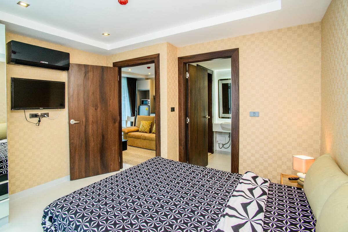 Ein Hotelzimmer mit Bett, Fernseher, Mikrowelle und einem durch eine offene Tür einsehbaren Badezimmer.