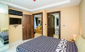 Ein Hotelzimmer mit Bett, Fernseher, Mikrowelle und einem durch eine offene Tür einsehbaren Badezimmer.
