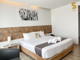 Habitación de hotel con cama, mesita de noche, lámpara, una obra de arte en la pared y un logo en la pared.