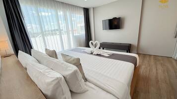 Ett hotellrum med en stor säng, en tv på väggen och utsikt över omgivningarna.