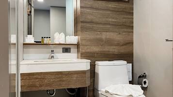 Un baño moderno con tocador de madera, inodoro, ducha y perchero.