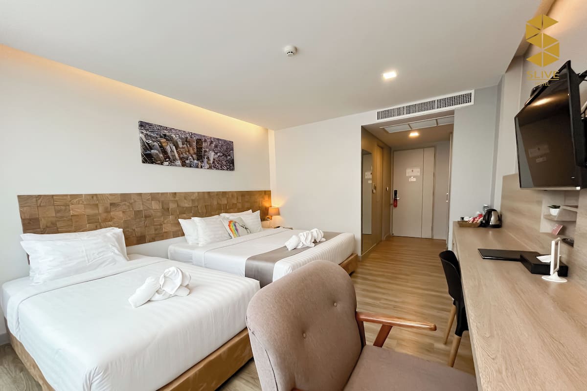 Ein Hotelzimmer mit zwei Betten, einem Fernseher, einem Schreibtisch und einem Sessel.
