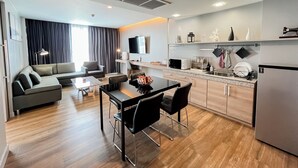 A modern hotel room with a living area, dining space, and kitchenette.