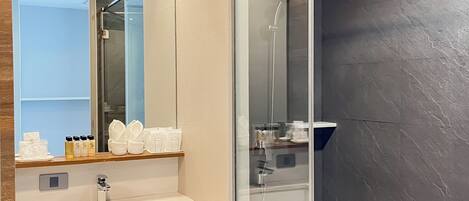 Een moderne badkamer met een douchecabine van glas, een wastafelmeubel met spiegel en een wastafel.