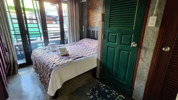 Un dormitorio con una cama, una puerta verde y vistas al exterior.