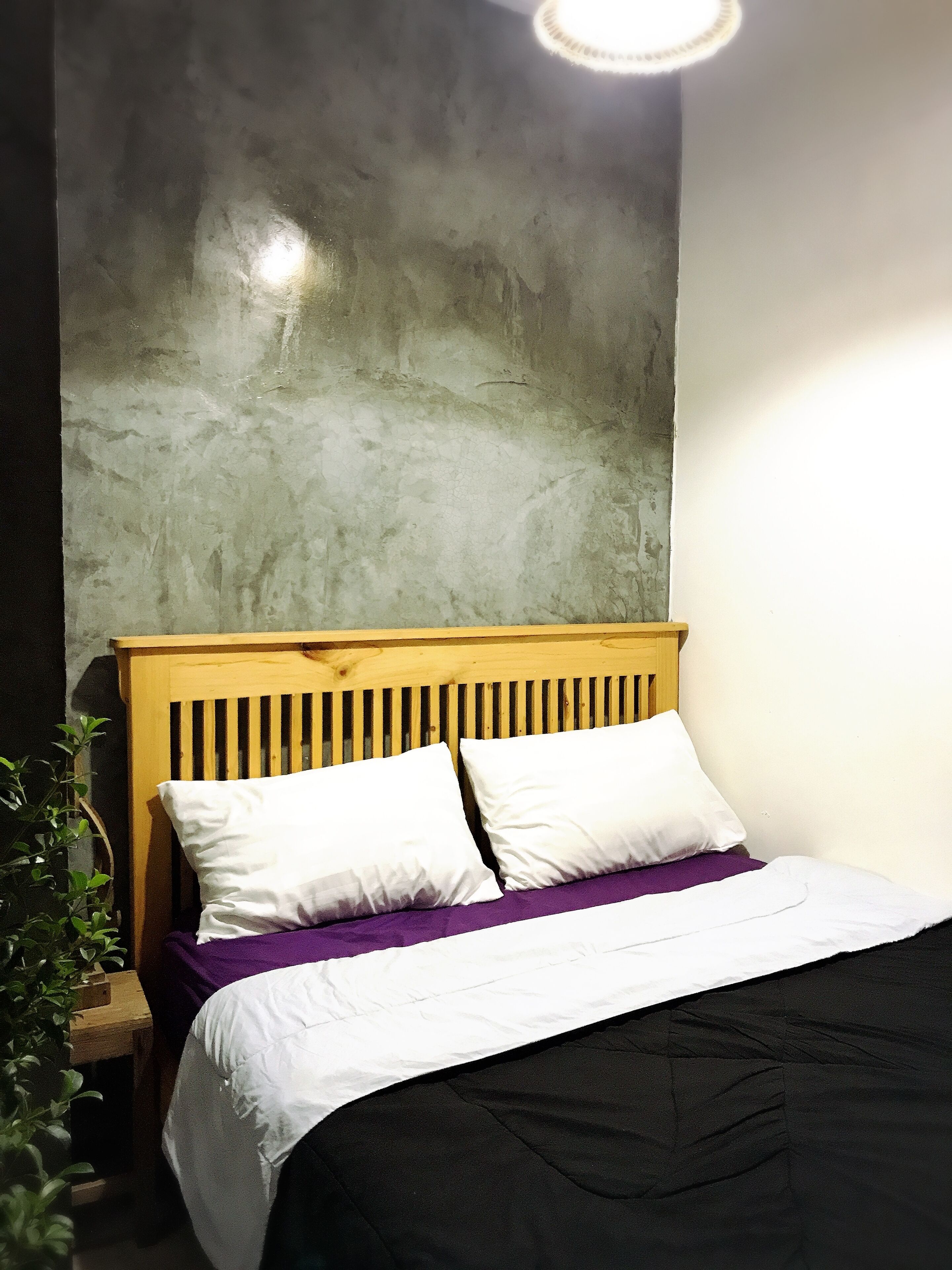 A bed with a wooden headboard, white pillows, and a black bedspread.