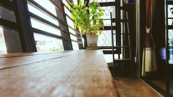 Una mesa de madera en una habitación con una planta en maceta, una silla y un ventanal con vistas al exterior.