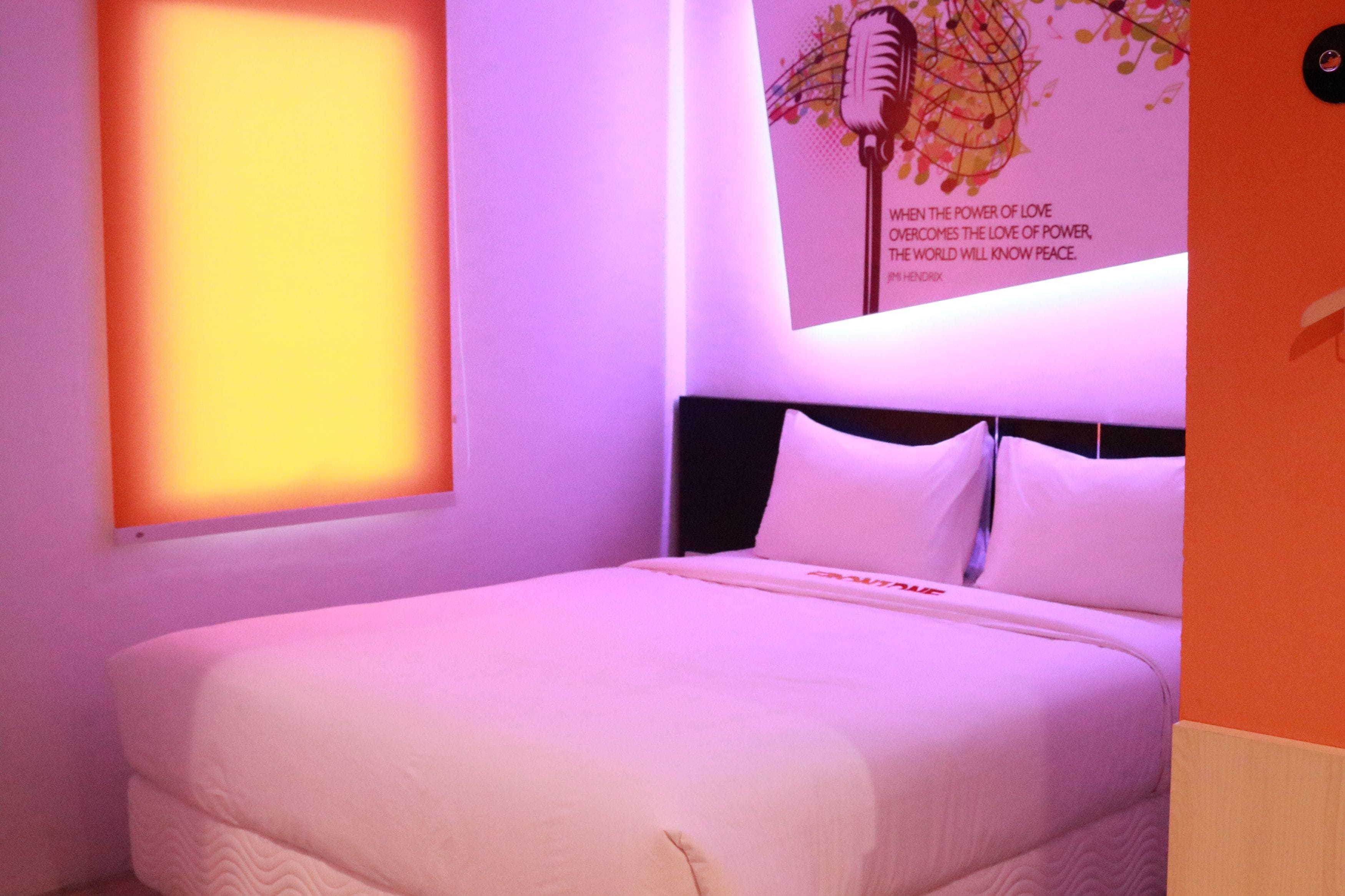A neatly made bed in a room with a large poster on the wall and a window with a view.