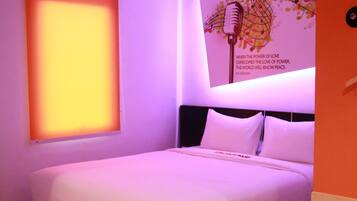 A neatly made bed in a room with a large poster on the wall and a window with a view.