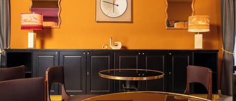 Una habitación con una mesa redonda, dos sillas, un reloj en la pared y un armario.
