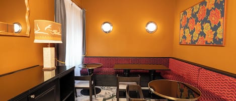 Ein Restaurantinneres mit Marmorboden, rot gemusterten Sitzmöglichkeiten und runden Tischen.