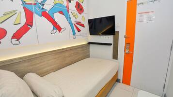 Quarto de hotel com uma cama, uma televisão e uma parede com um pôster.