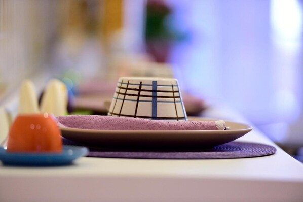 A table with a patterned bowl, a plate with a dessert, and a blue plate with an orange item. - Madì B&B (Rome)