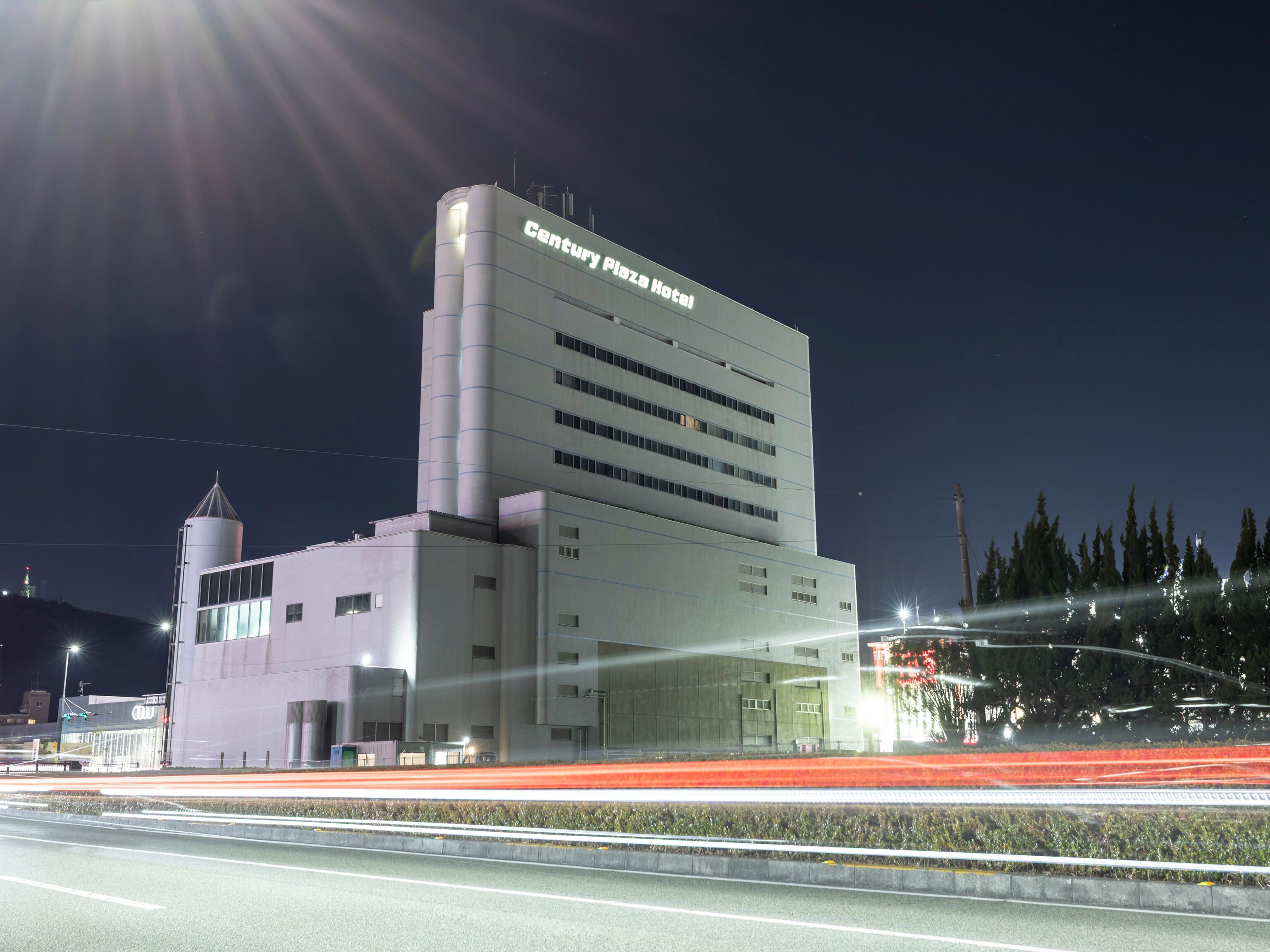 A modern hotel with a prominent cylindrical tower and a flat roof.