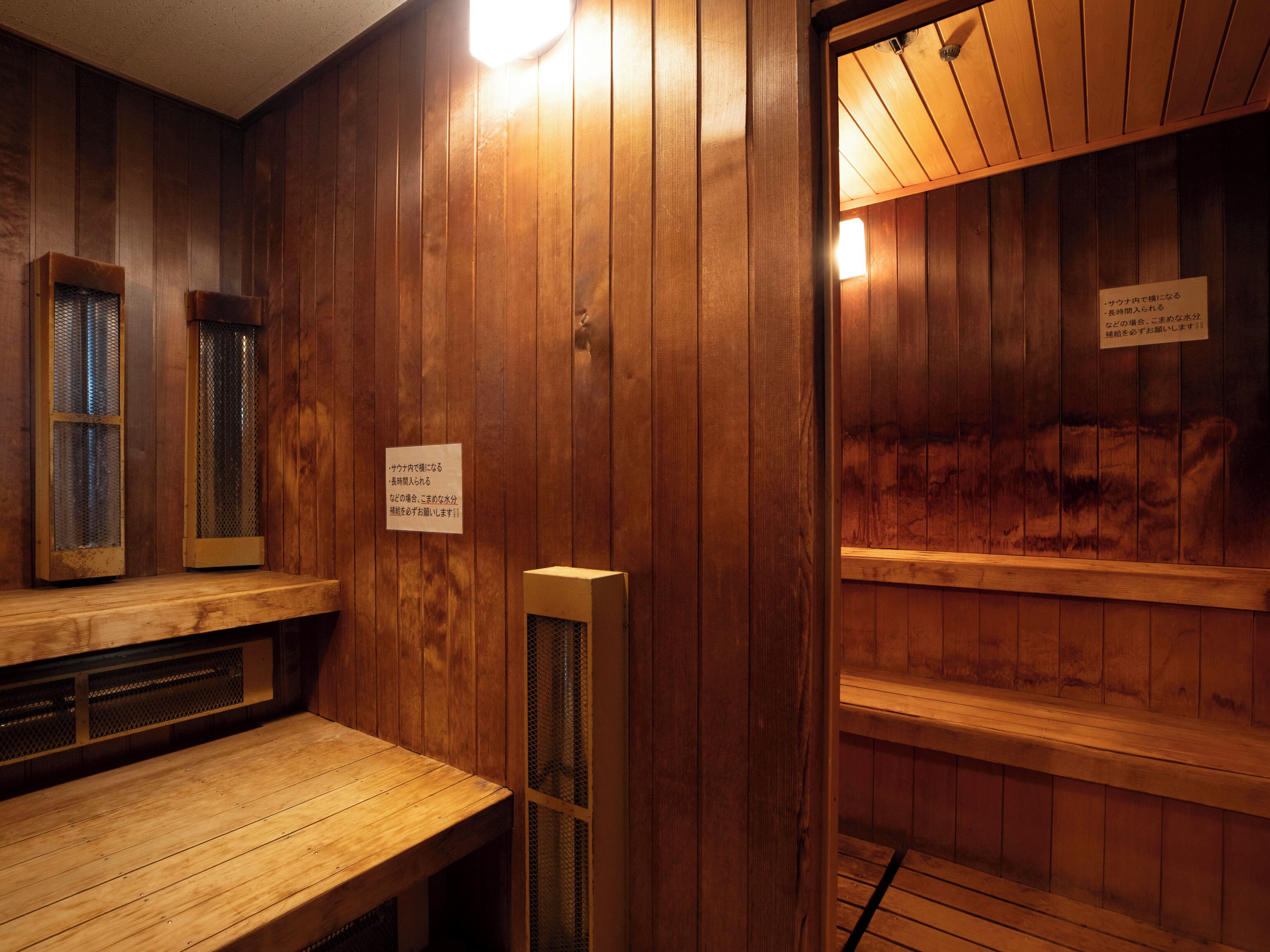 Une salle de sauna avec des murs et des bancs en bois. On y trouve une pancarte avec du texte en japonais.