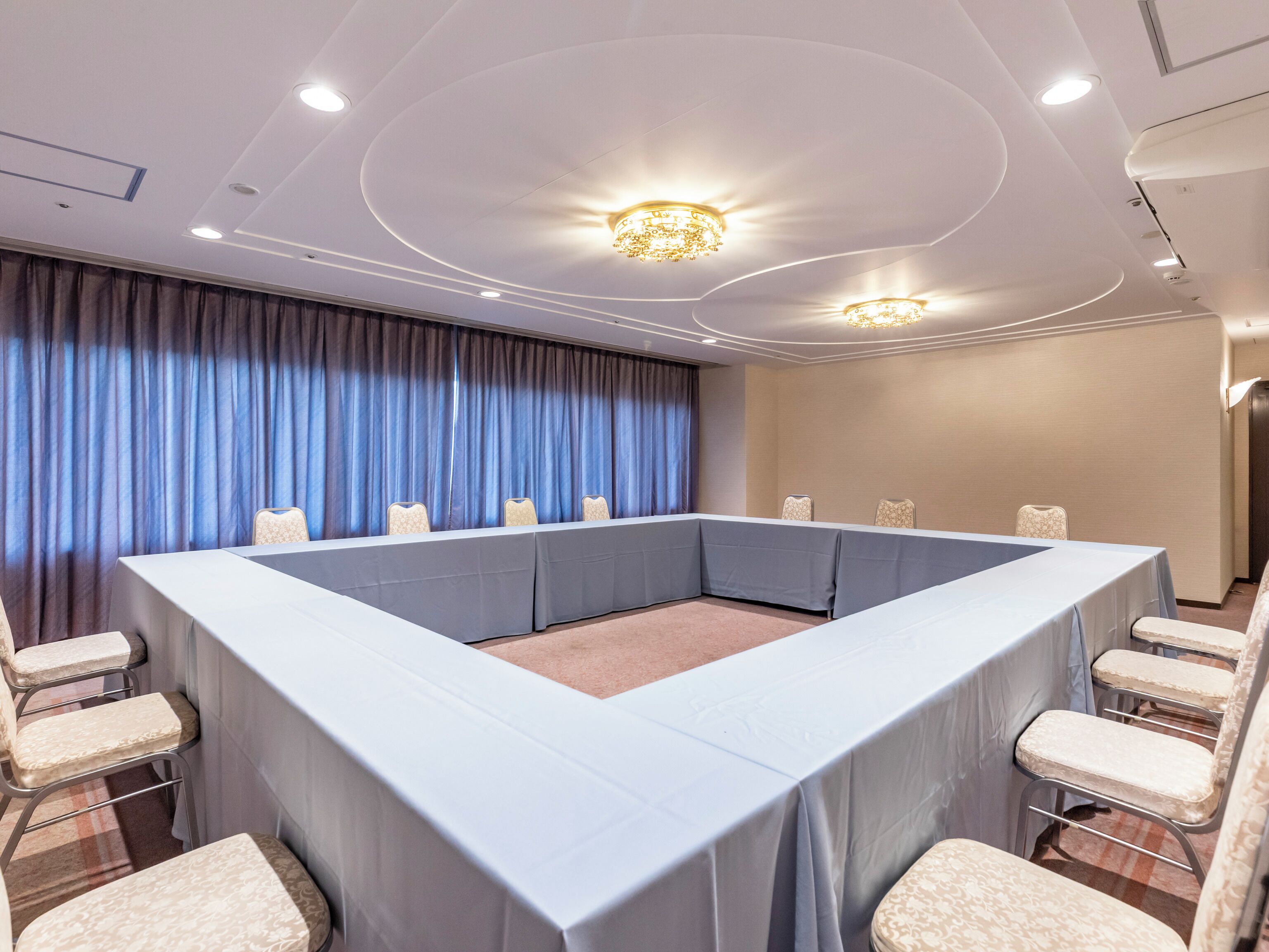 A conference room with a large table, chairs, and a chandelier.