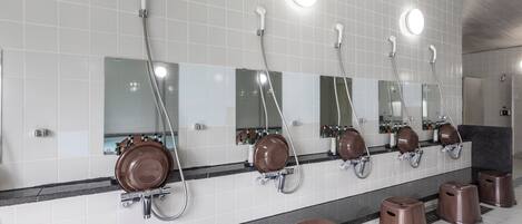 Un baño público con varios lavamanos, espejos y cestos de basura.