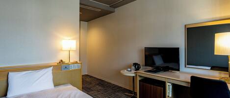 Habitación de hotel con cama, escritorio, silla y televisor.