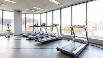 Une salle de sport équipée de tapis de course, d’un vélo d’appartement et d’un appareil d’aviron.