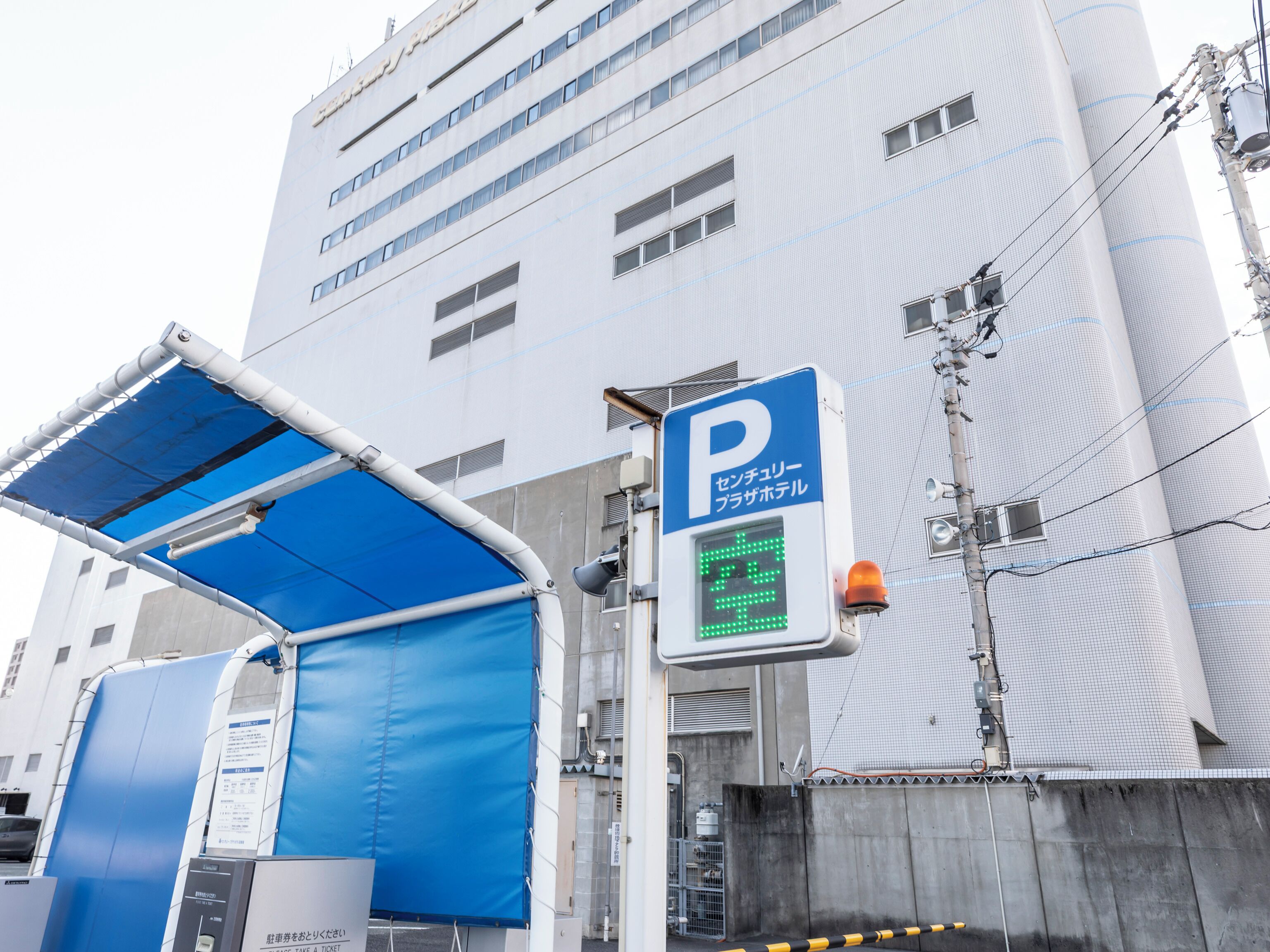 A parking structure with a blue canopy and a digital parking sign.